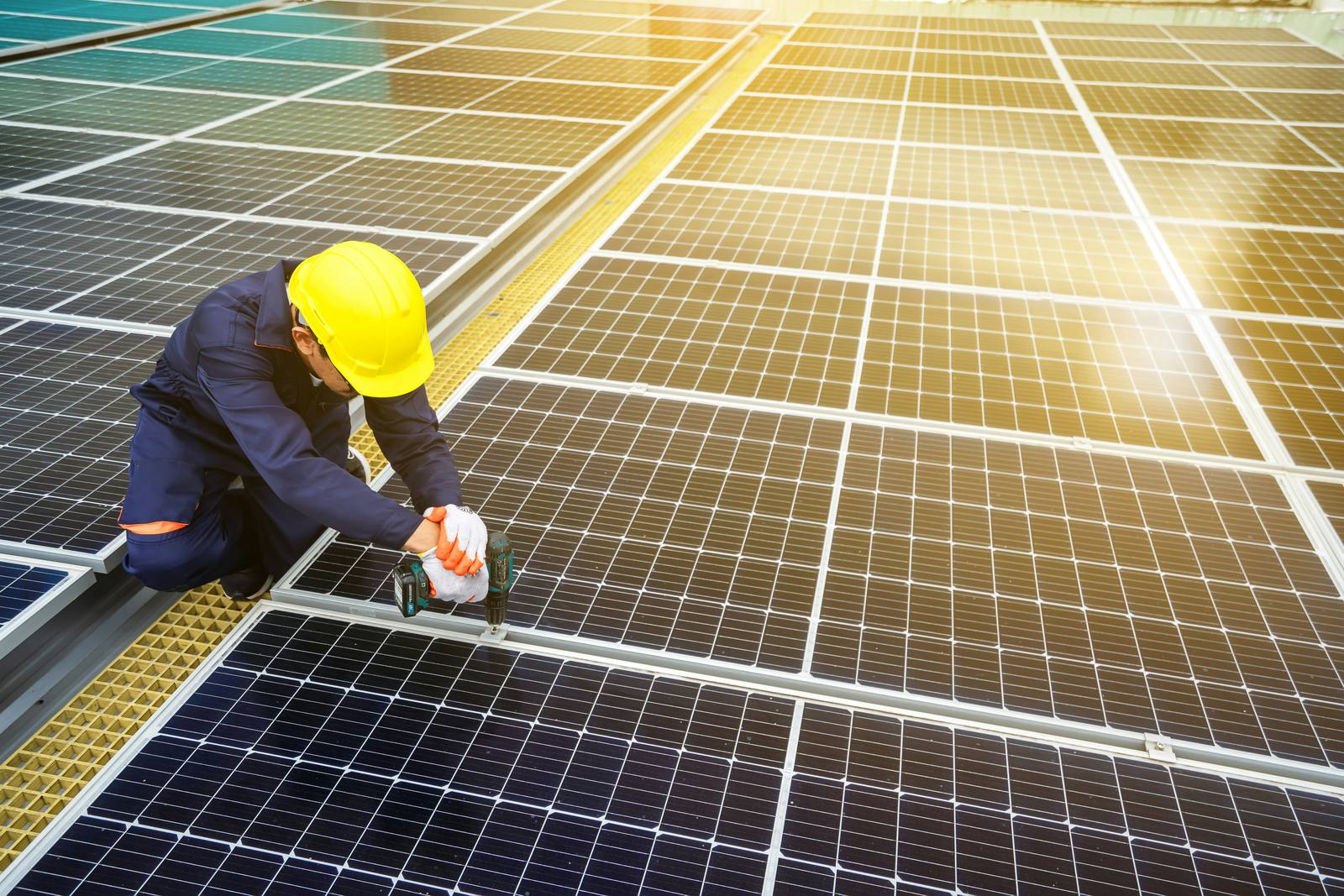 Installer fitting rooftop solar panels under a clear sky